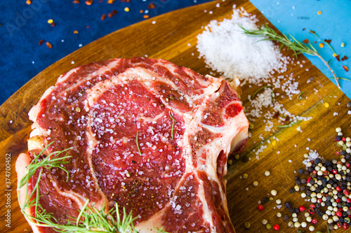 Raw beef meat on the table, spices and Rosemary, Rib eye steak ingredients. Pepper and coars salt. photo