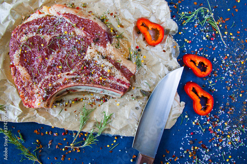 Raw beef meat on the table, spices and Rosemary, Rib eye steak ingredients. Pepper and coars salt. photo