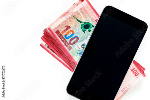 Bolivian currency, One hundred Bolivianos banknotes lying together with a mobile phone on a white background, Place for text photo