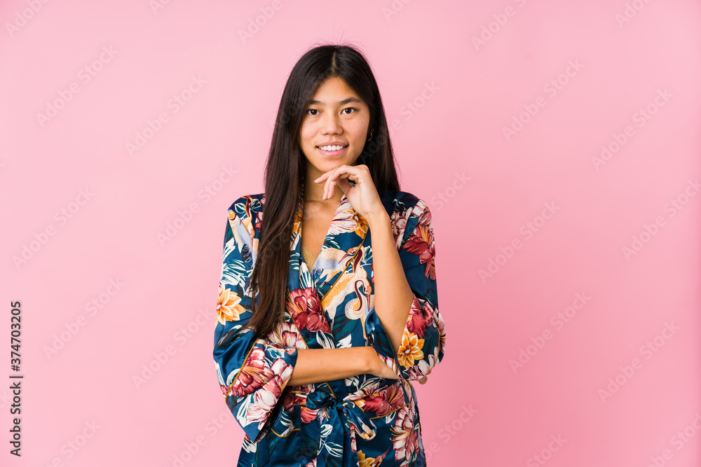 Young asian woman wearing a kimono pajamas smiling happy and confident, touching chin with hand. Young asian woman wearing a kimono pajamas smiling happy and confident, touching chin with hand.
