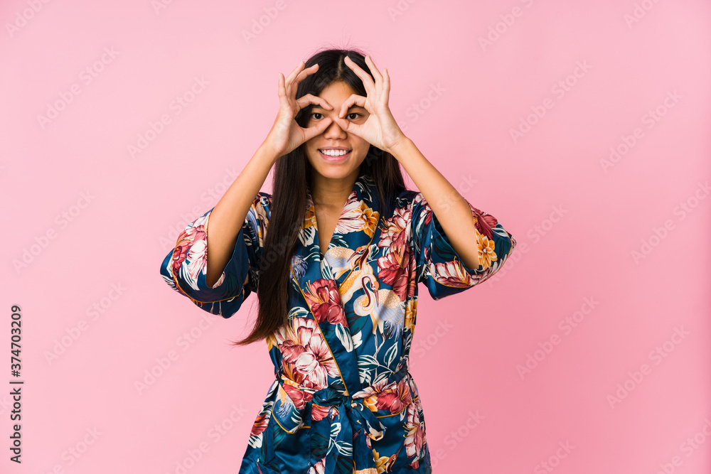 Young asian woman wearing a kimono pajamas showing okay sign over eyes Young asian woman wearing a kimono pajamas showing okay sign over eyes