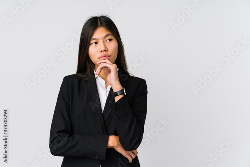 Young asian business woman looking sideways with doubtful and skeptical expression.