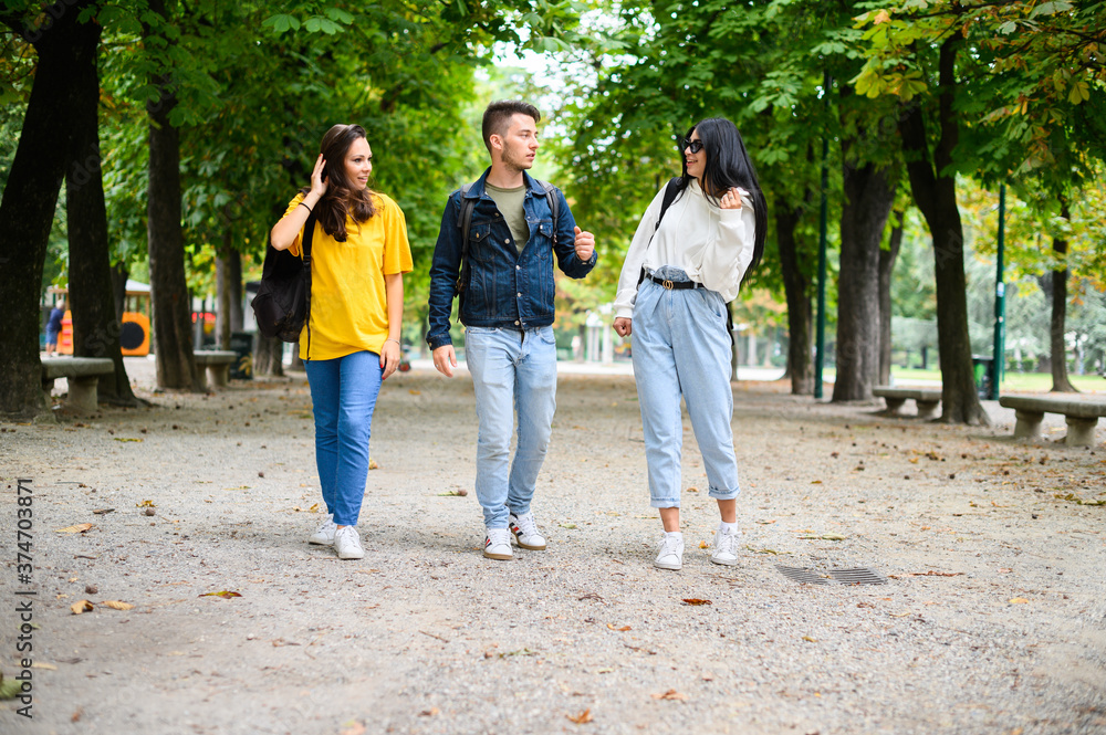 Happy students outdoor walking and talking to each other, full length Happy students outdoor walking and talking to each other, full length