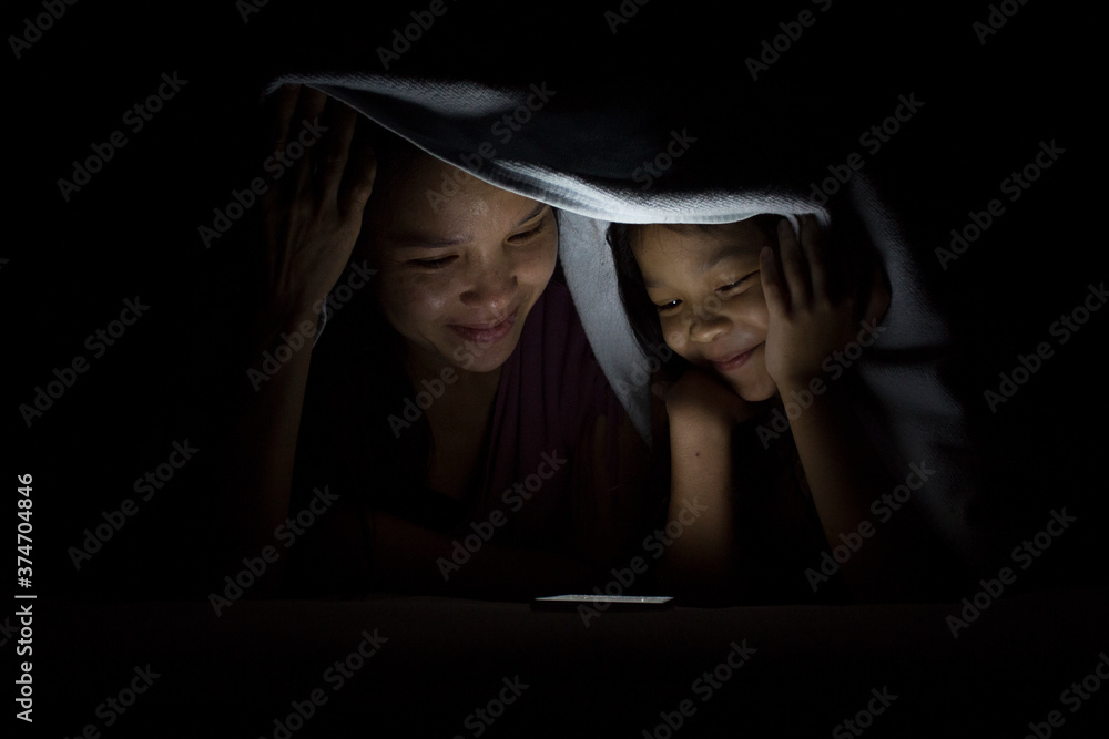 child and mom play smartphone under blanket child and mom play smartphone under blanket