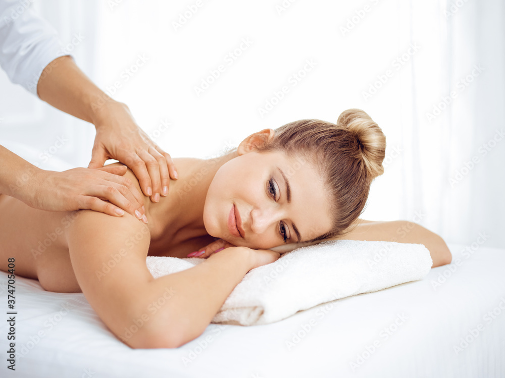 Young and blonde woman enjoying massage of back in spa salon. Beauty concept Young and blonde woman enjoying massage of back in spa salon. Beauty concept