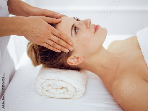 Young and blonde woman enjoying facial massage in spa salon. Beauty concept © Iryna