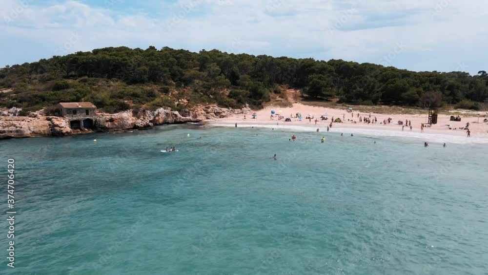 Aerial establishing shot of tourists relaxing on S'Amarador beach, an unspoilt beach in Mallorca Aerial establishing shot of tourists relaxing on S'Amarador beach, an unspoilt beach in Mallorca