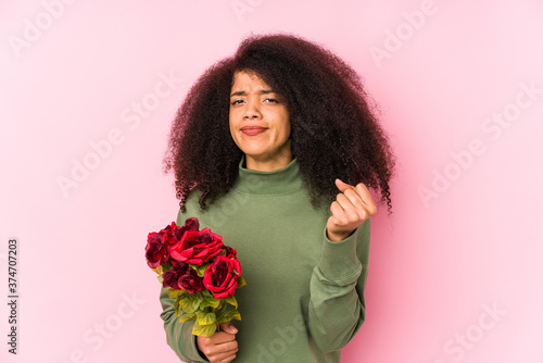 Young afro woman holding a roses isolated Young afro woman holding a rosesshowing fist to camera, aggressive facial expression.