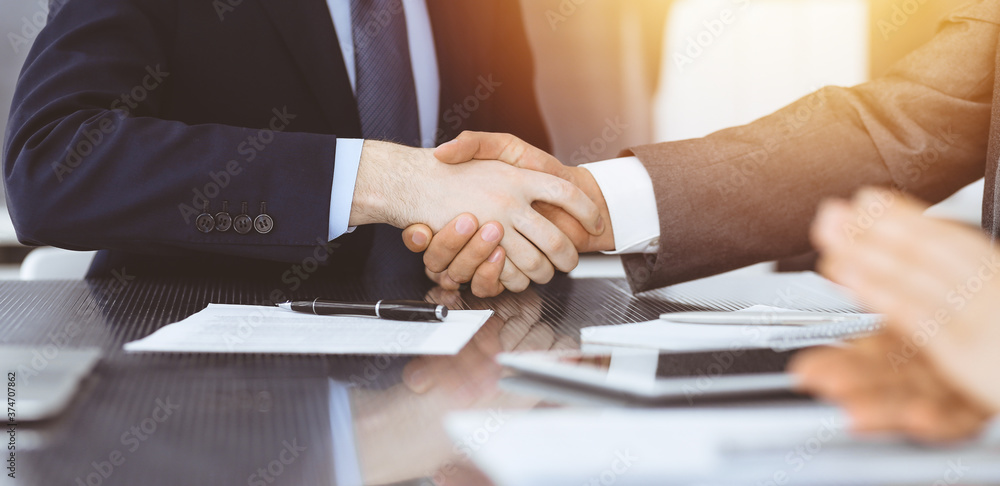 Handshake as successful negotiation ending, close-up. Unknown business people shaking hands after contract signing in modern office Handshake as successful negotiation ending, close-up. Unknown business people shaking hands after contract signing in modern office