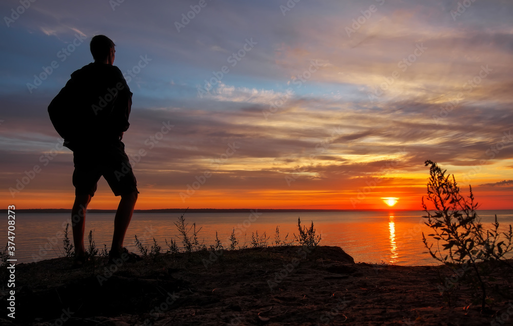 Fototapeta premium Young man standing at sunset. Sea in the morning.