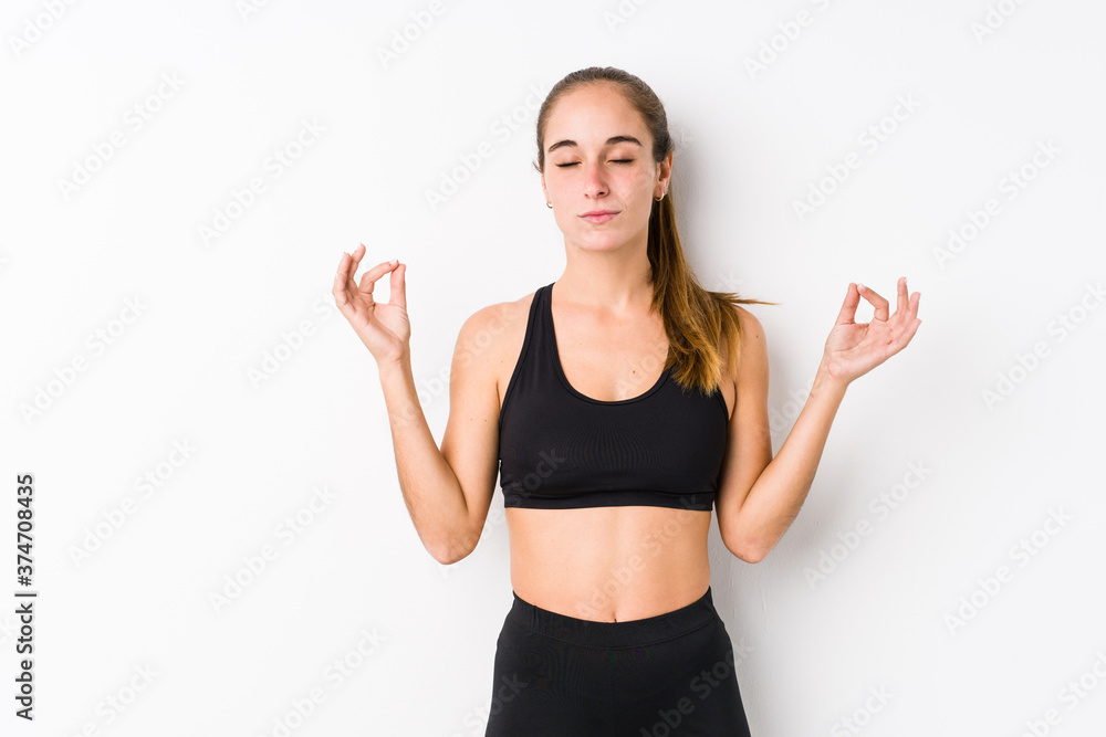Young caucasian fitness woman posing in a white background relaxes after hard working day, she is performing yoga. Young caucasian fitness woman posing in a white background relaxes after hard working day, she is performing yoga.