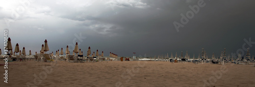 Italian coasts with rough sea due to the late summer storm  cloudy sky  closed umbrellas and cold temperature  end of tourism and holidays and beginning of autumn