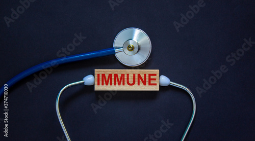 Wooden block with word 'immune' and stethoscope on black background. Medical concept.