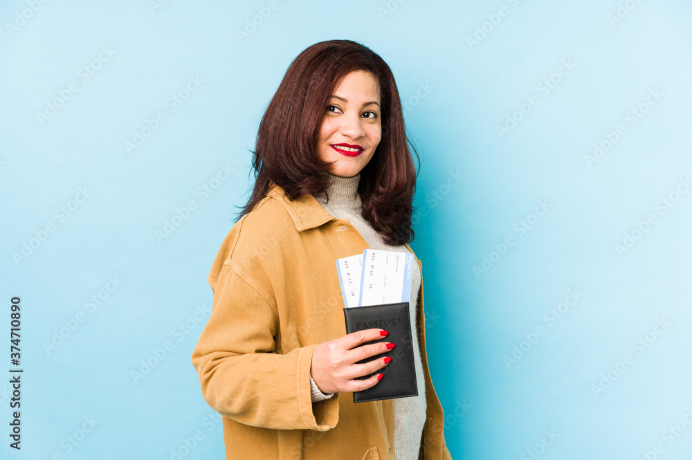 Middle age latin woman holding a passport isolated looks aside smiling, cheerful and pleasant. Middle age latin woman holding a passport isolated looks aside smiling, cheerful and pleasant.