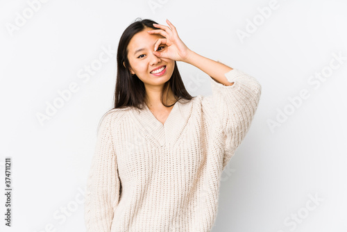 Young chinese woman isolated excited keeping ok gesture on eye.
