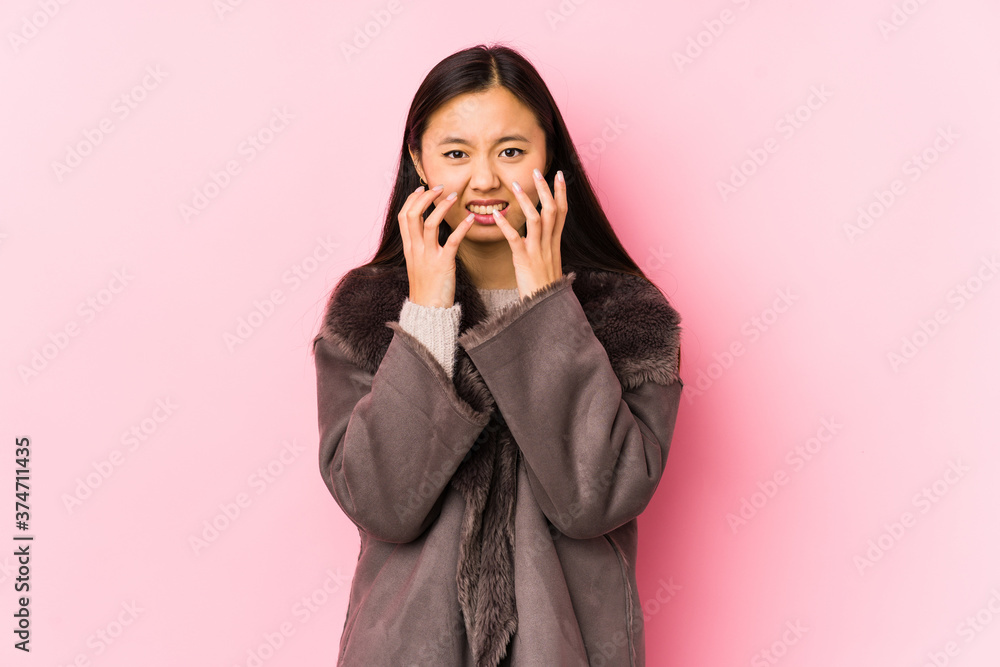 Young chinese woman wearing a coat isolated upset screaming with tense hands. Young chinese woman wearing a coat isolated upset screaming with tense hands.