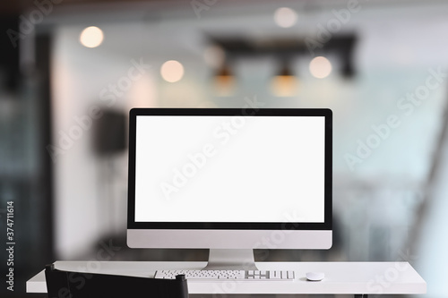 Workspace computer monitor with a white blank screen on white table.