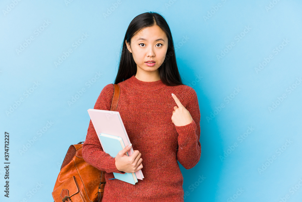 Obraz premium Young chinese student woman isolated pointing with finger at you as if inviting come closer.