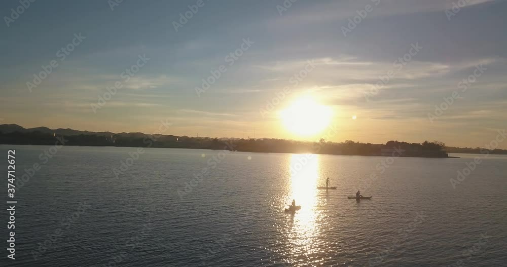 Aerial drone shot of friends doing kayak and paddle boarding at the lake during sunset Aerial drone shot of friends doing kayak and paddle boarding at the lake during sunset
