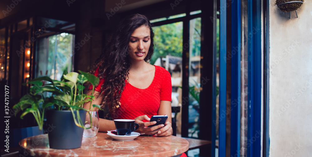 Young ethnic female using smartphone in cafe