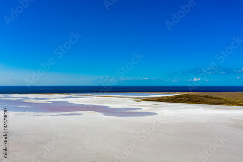 Fototapeta Naklejka Na Ścianę i Meble -  White lake, covered with salt, against the blue sea and sky. The view from the top.