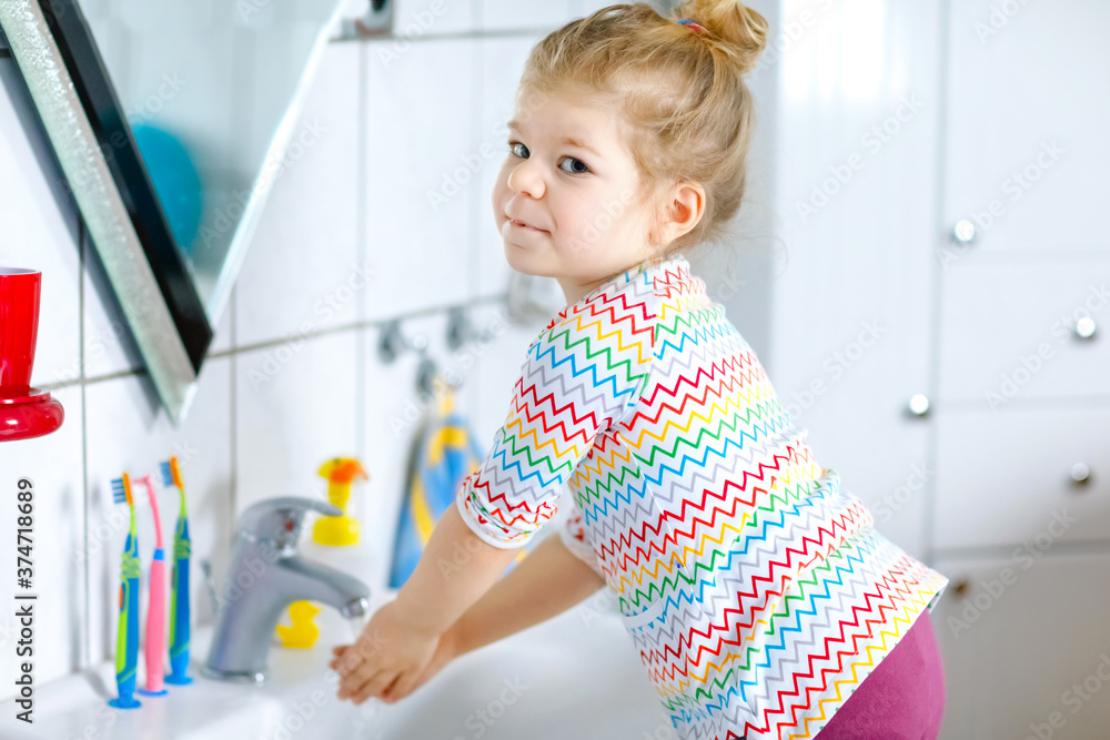 Cute little toddler girl washing hands with soap and water in bathroom. Adorable child learning cleaning body parts. Hygiene routine action during viral desease. kid at home or nursery. Cute little toddler girl washing hands with soap and water in bathroom. Adorable child learning cleaning body parts. Hygiene routine action during viral desease. kid at home or nursery.