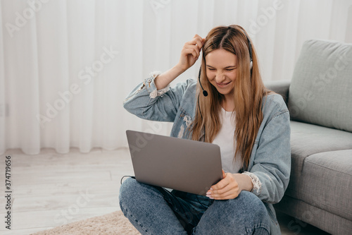 Smiling young teenage girl wear headphones video calling on laptop. Happy woman looking at computer screen watching webinar or doing video chat by webcam.