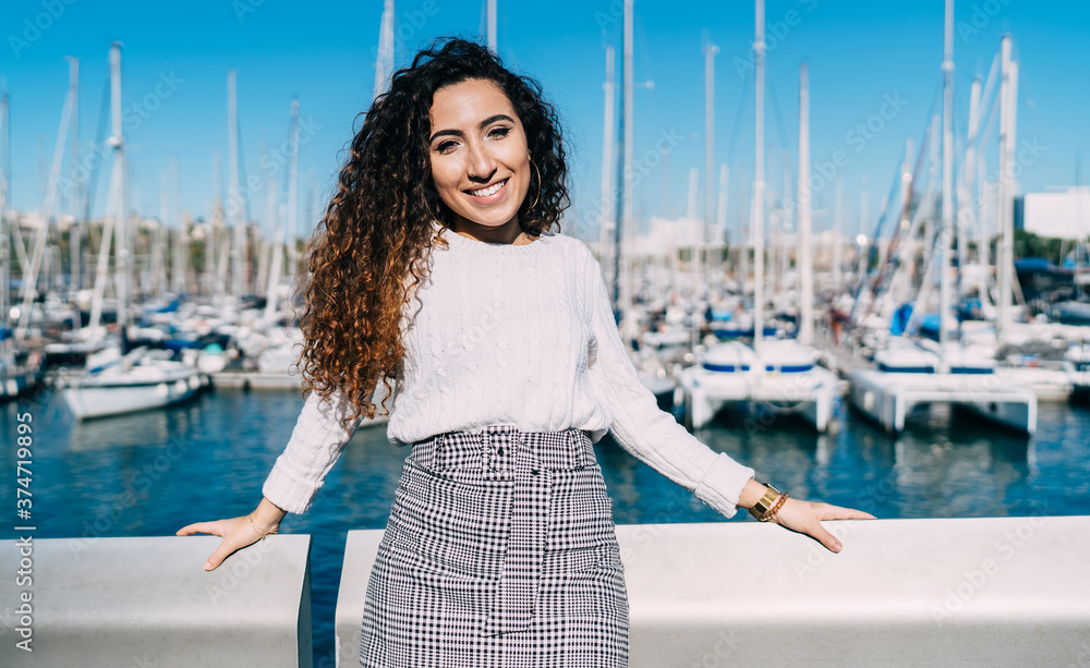 Cheerful young ethnic woman standing in yacht club