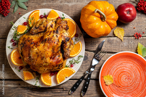 Thanksgiving autumn compositions. Roasted chicken or turkey with citrus and spices for celebrations thanksgiving day on wooden table. Festive table settings for thanksgiving dinner. Top view