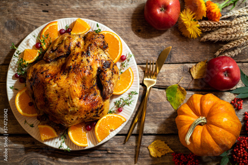 Baked chicken for Thanksgiving Day. Roasted chicken or turkey with citrus and spices for celebrations thanksgiving day on wooden table. Festive table settings for thanksgiving dinner. Top view