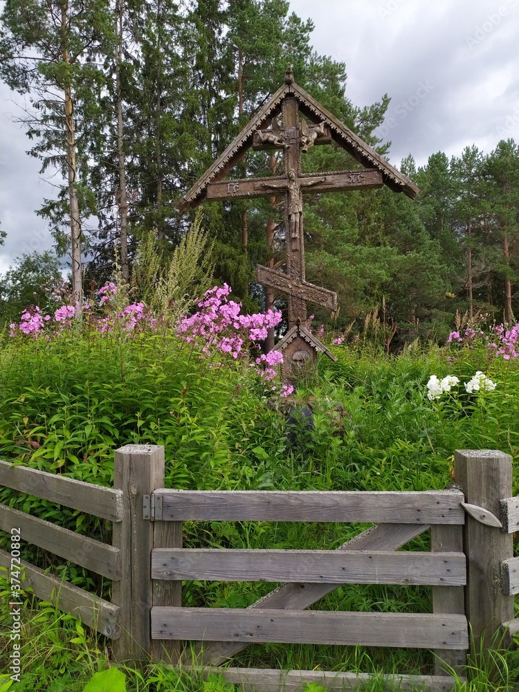 Old wooden Russian orthodox cross among flowers in the forest Old wooden Russian orthodox cross among flowers in the forest