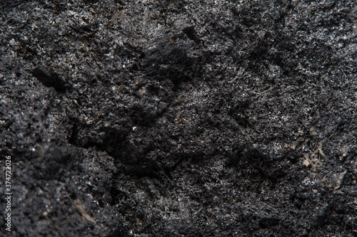 Blurred black background in soft focus with hard coal at high magnification. An image on the theme of geology and the extraction of minerals and natural fuels.