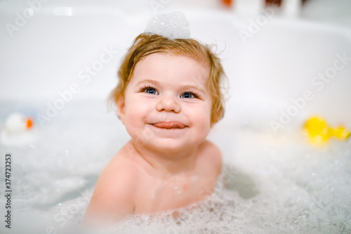 Photographie Cute adorable baby girl taking foamy bath in bathtub