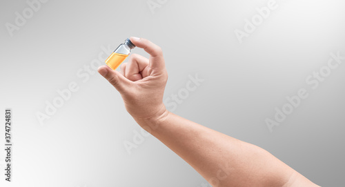 Doctor hand inspecting orange medical drug. Bright grey background. Medical concept for health care, reseach, and science.