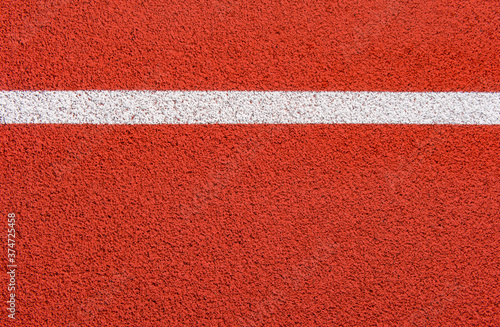 Close up on a white line in artificial red turf, on a street basketball, handball, volleyball, futsal, rugby, hockey and football field, in a sports background © Augustas Cetkauskas