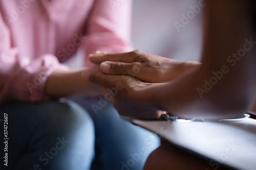 Close up African American psychotherapist holding clipboard  touching patient hands  expressing empathy and support at meeting  counselor therapist comforting girl during personal therapy session