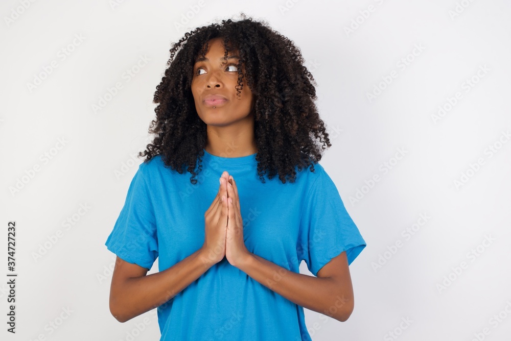 Young african woman with curly hair wearing casual blue shirt over white background making up plan in mind holding hands together, setting up an idea. Young african woman with curly hair wearing casual blue shirt over white background making up plan in mind holding hands together, setting up an idea.