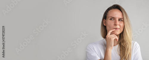 Puzzled perplexed young woman with distrustful face isolated on grey studio wall, unbelieving suspicious girl looking aside doubtful uncertain photo