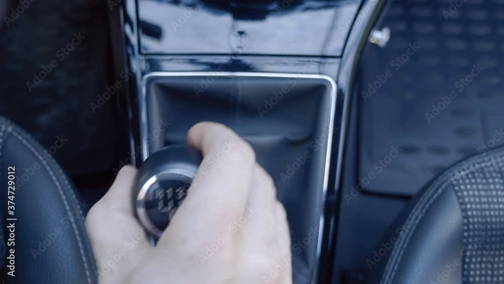 Added shaking from moving the car! The driver's hand takes a shiny black lever and engages the gears in the manual transmission. Closeup. Top view Added shaking from moving the car! The driver's hand takes a shiny black lever and engages the gears in the manual transmission. Closeup. Top view