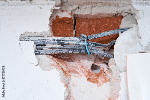 Old electrical cables in a brick wall. Danger wiring photo