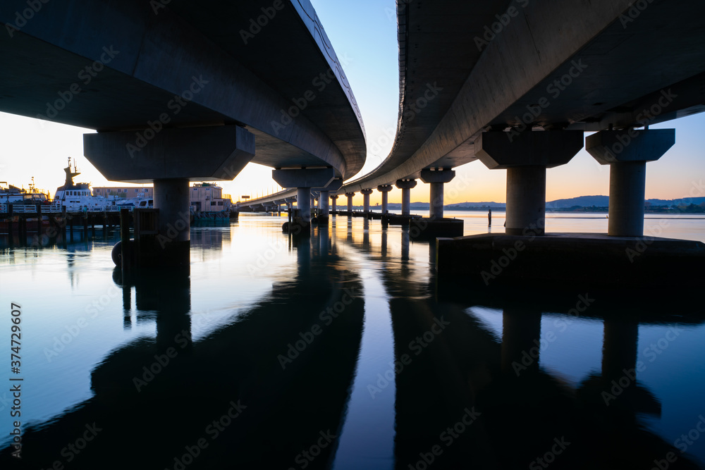 Curving lines and calm water under Tauranga Harbour Bridge at sunrise. Curving lines and calm water under Tauranga Harbour Bridge at sunrise.