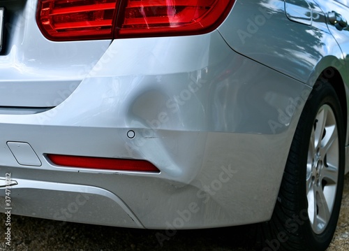 Backside of car has dented rear bumper damaged after accident in the parking lot.