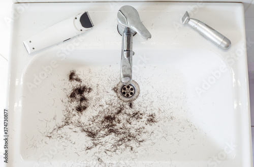 Foto Shaved hairs in the washbasin with razor and trimmer