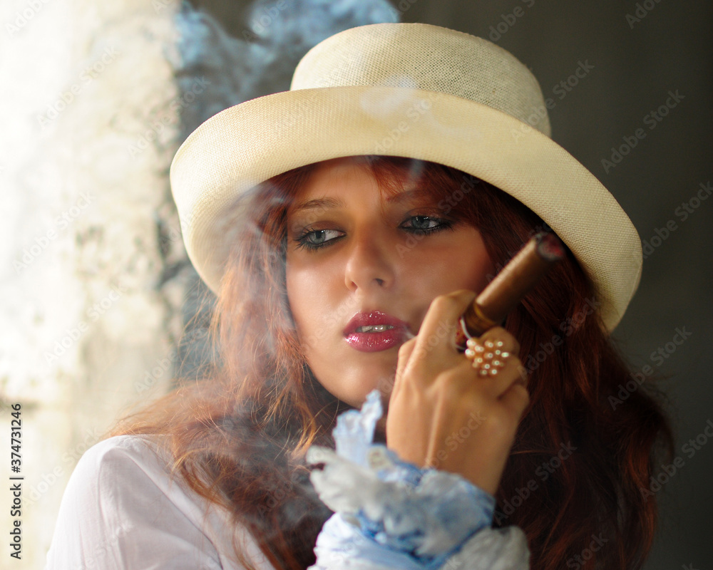 Elegant smoking woman. Portrait of a red-haired girl with a cigar