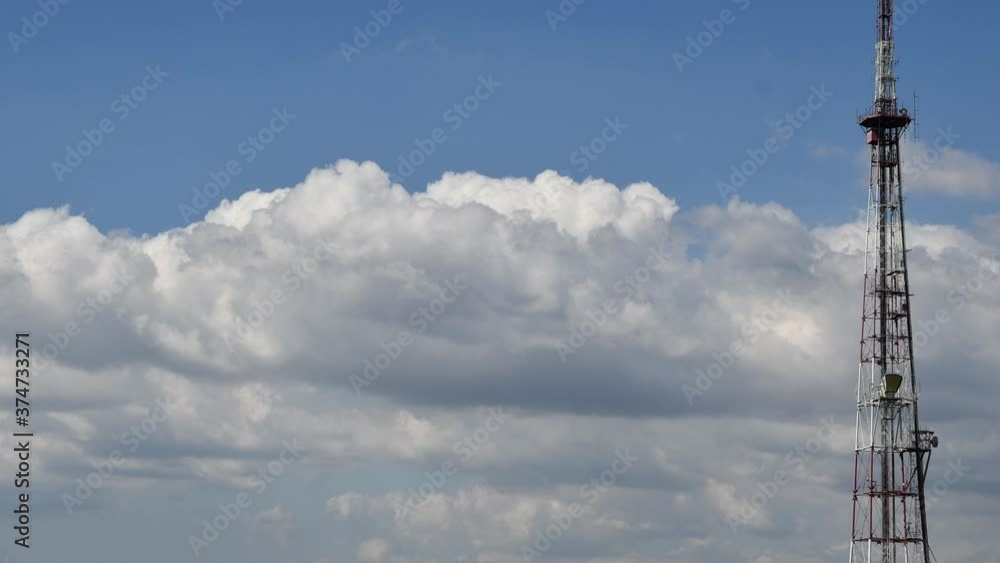 Time lapse of cloudscape with industrial communication tower antennas transmitting data, repeaters for mobile communications. 5G tower with moving white clouds Time lapse of cloudscape with industrial communication tower antennas transmitting data, repeaters for mobile communications. 5G tower with moving white clouds