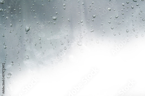 Raindrops on window glasses surface with cloudy background .