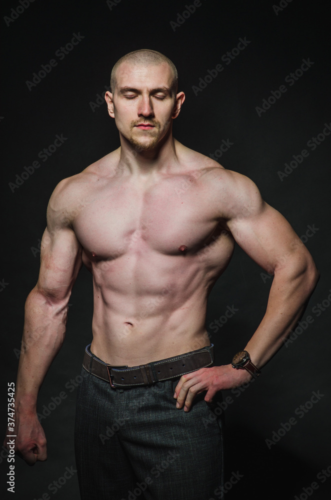 Fototapeta premium Sporty sexy man stands Topless on a dark background. Sports, beauty