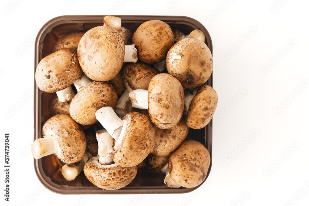 Fresh mushrooms in plastic container isolated on white background, close up view directly from above Fresh mushrooms in plastic container isolated on white background, close up view directly from above