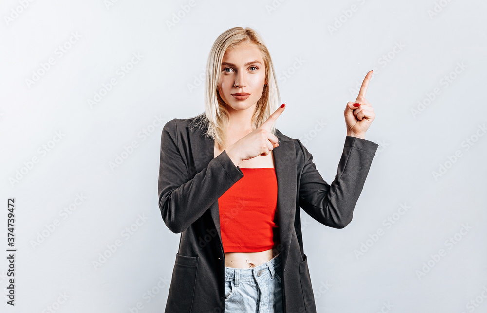 Portrait of a smiling girl pointing finger up at copyspace isolated on a white background. A woman points to an idea, a place for advertising. Positive blonde. Portrait of a smiling girl pointing finger up at copyspace isolated on a white background. A woman points to an idea, a place for advertising. Positive blonde.