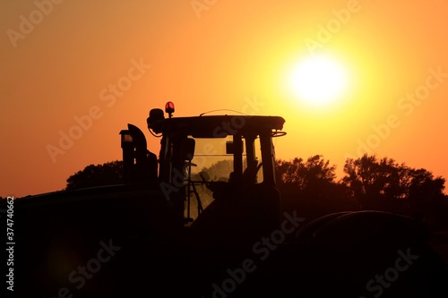 silhouette of a sunset with a Tractor in a field  in Kansas.